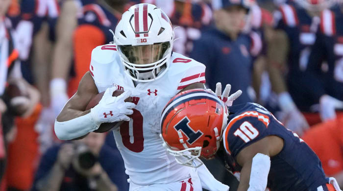 Wisconsin’s Braelon Allen stiff arms Illinois defender.